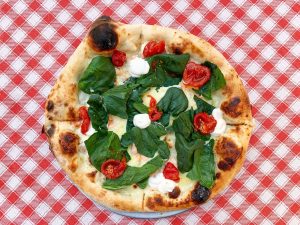 pizza with green leaves on white ceramic plate