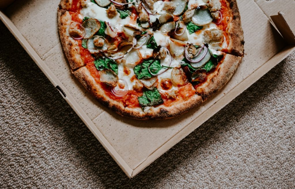 pizza with green leaves on brown box
